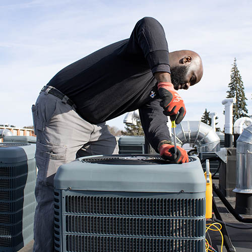 Gas Doctor technician removing a fan shroud from an AC compressor