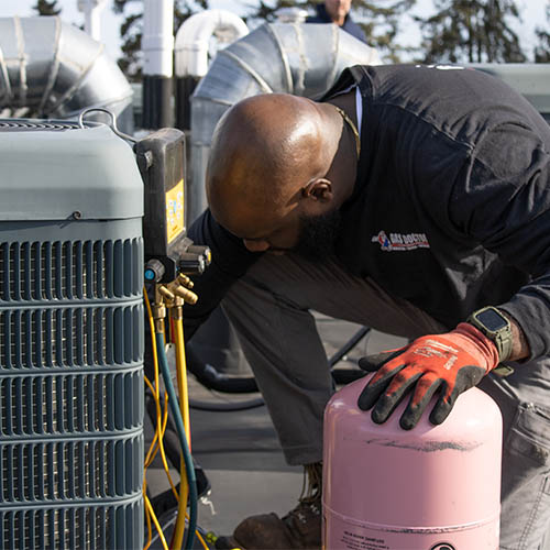 Gas Doctor technician checking refrigerant connections on AC compressor